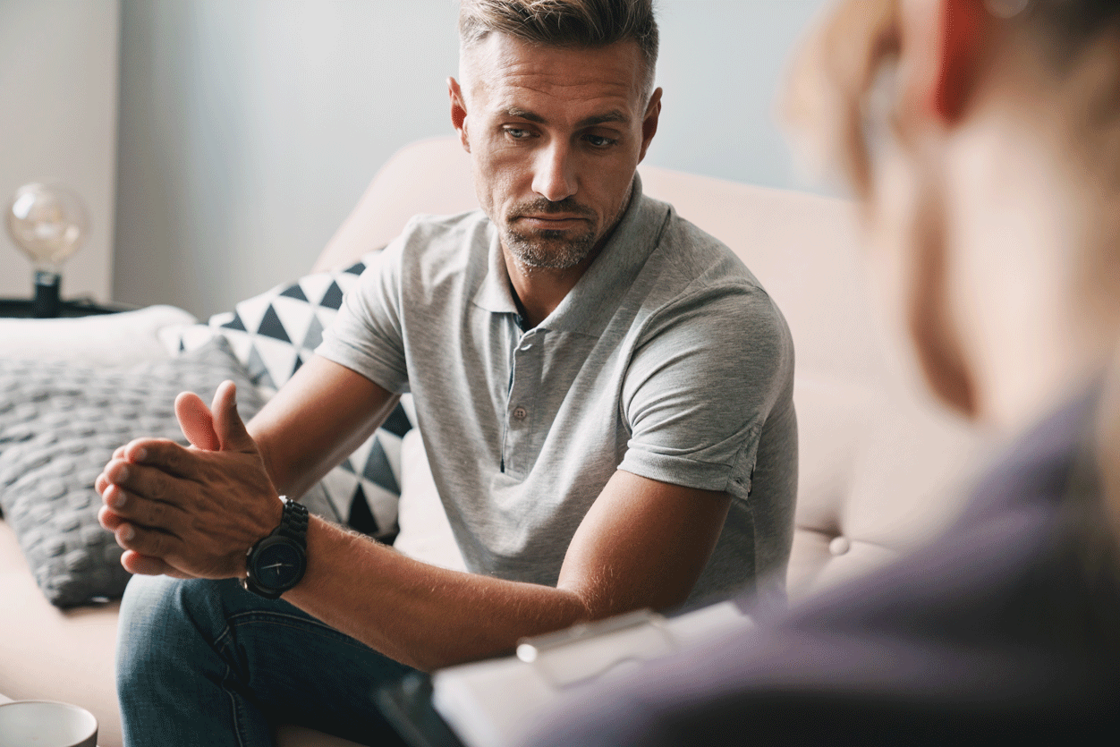 A man talks to a woman who is holding a clipboard.