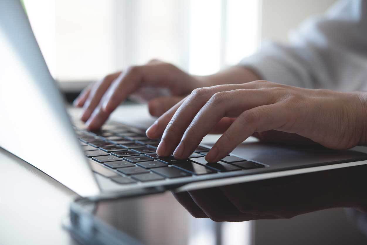 Close-up of a man typing on a laptop.