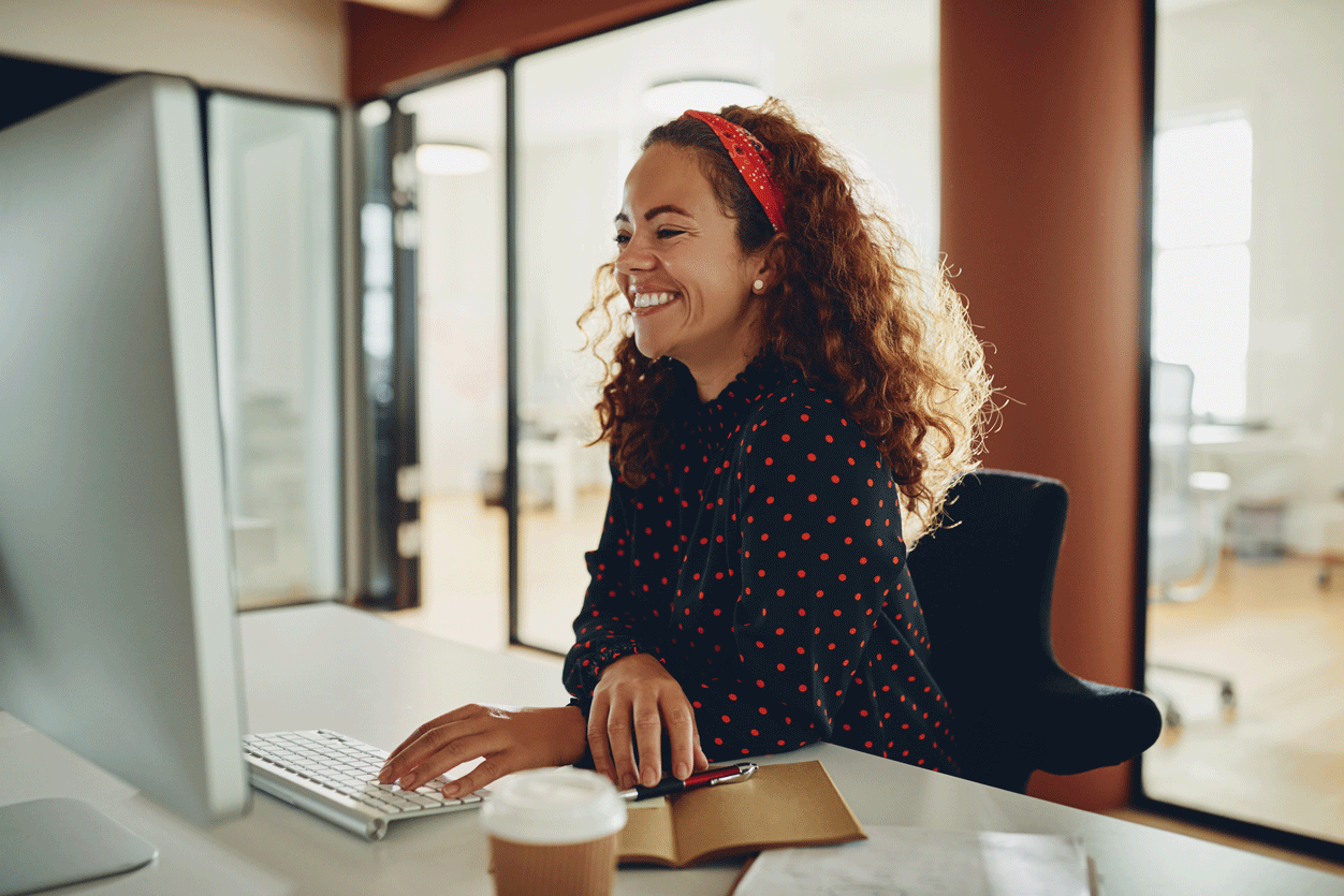 Woman sitting at computer and smiling.